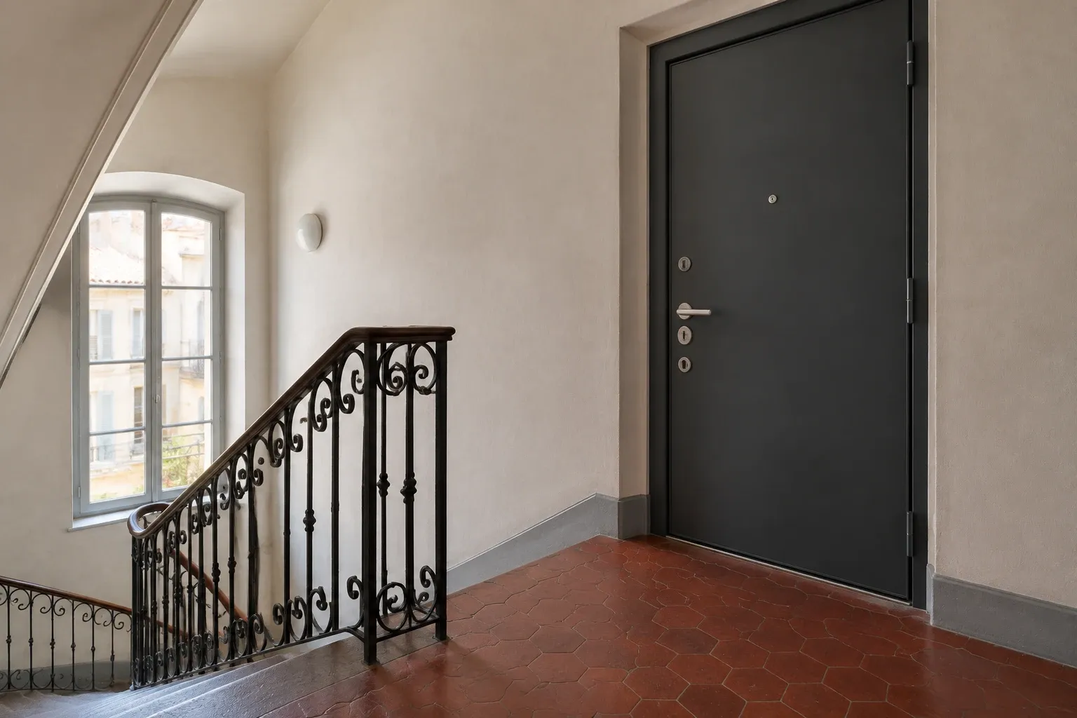 Porte palière blindée anthracite dans un immeuble ancien de Marseille, tomettes et rampe en fer forgé